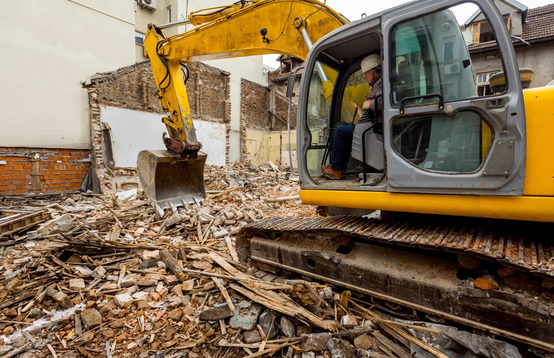 Excavator in the rubble of a partly demolished building